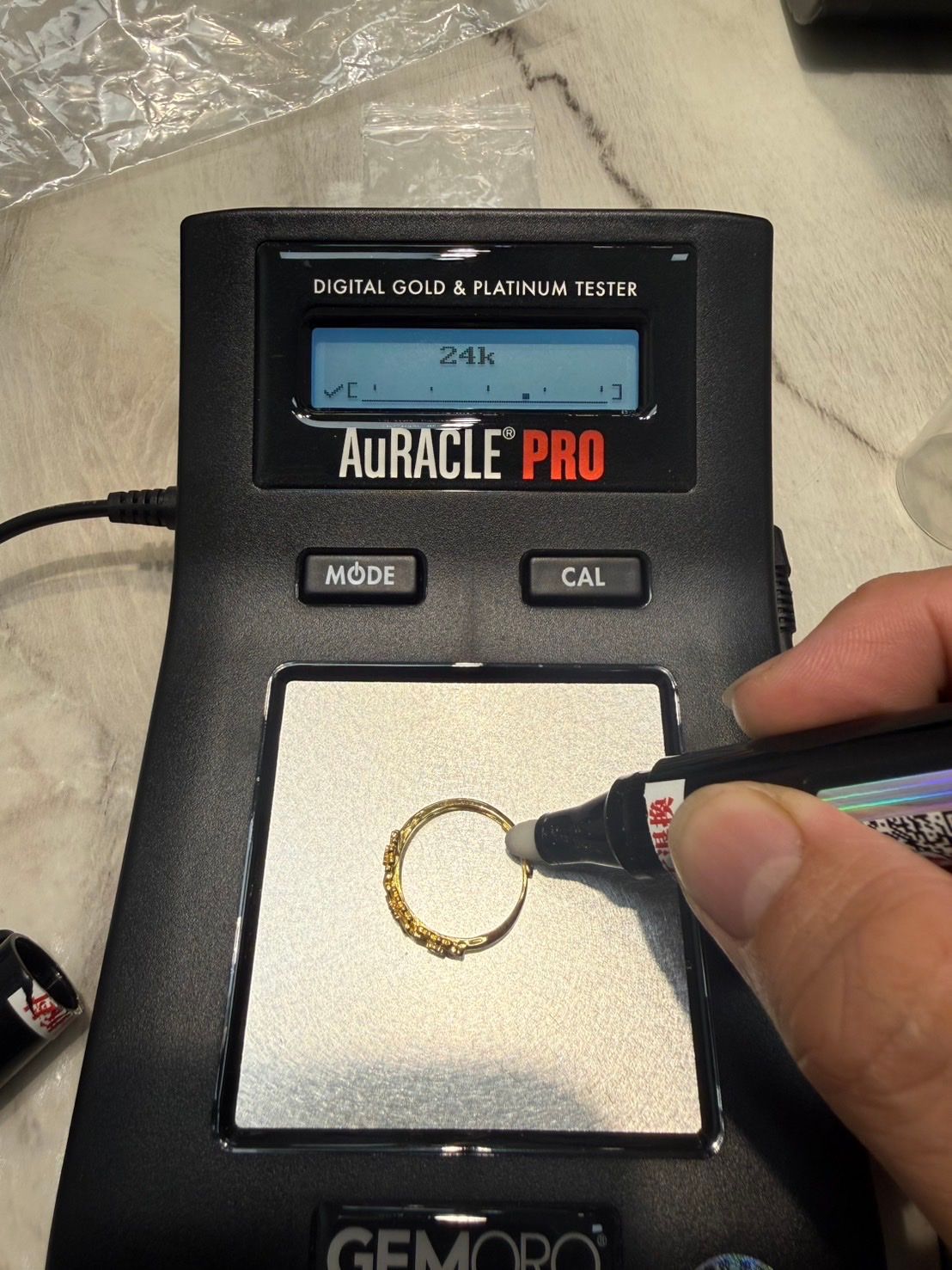 店內以 AuRACLE PRO 黃金測試儀檢測金飾外層成色,螢幕顯示 24k
